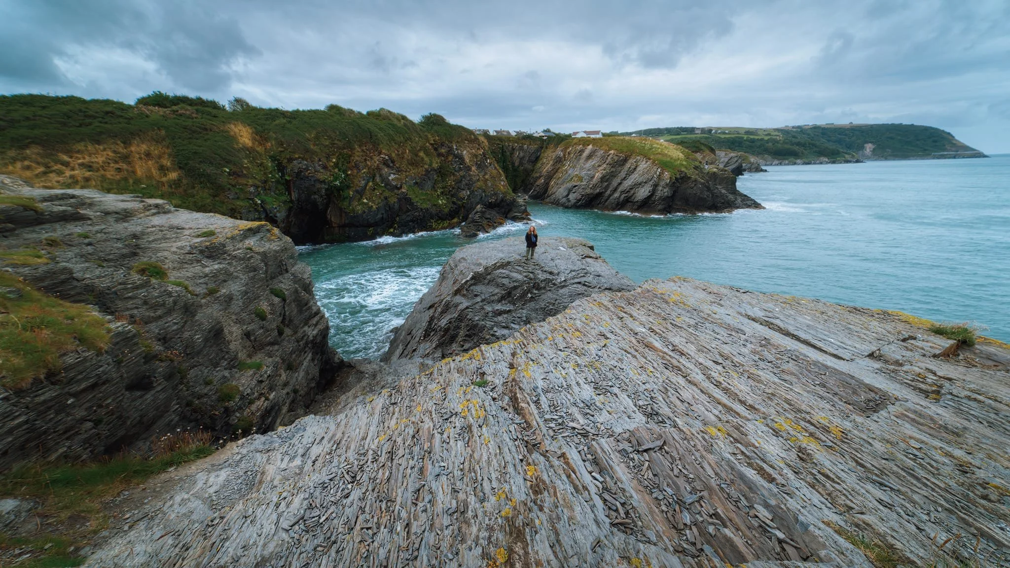  We found a rough cut trail leading down from one of the cliffs, which got us down to this fantastic crag. I quickly equipped my 14mm ultra-wide angle lens, seeking to accentuate the lines created by the foreground rock as well as capture the vast coastal scene. My lovely Lisabet had already hopped skipped and jumped onto the crag, and graciously posed for a shot to give a good sense of scale. 