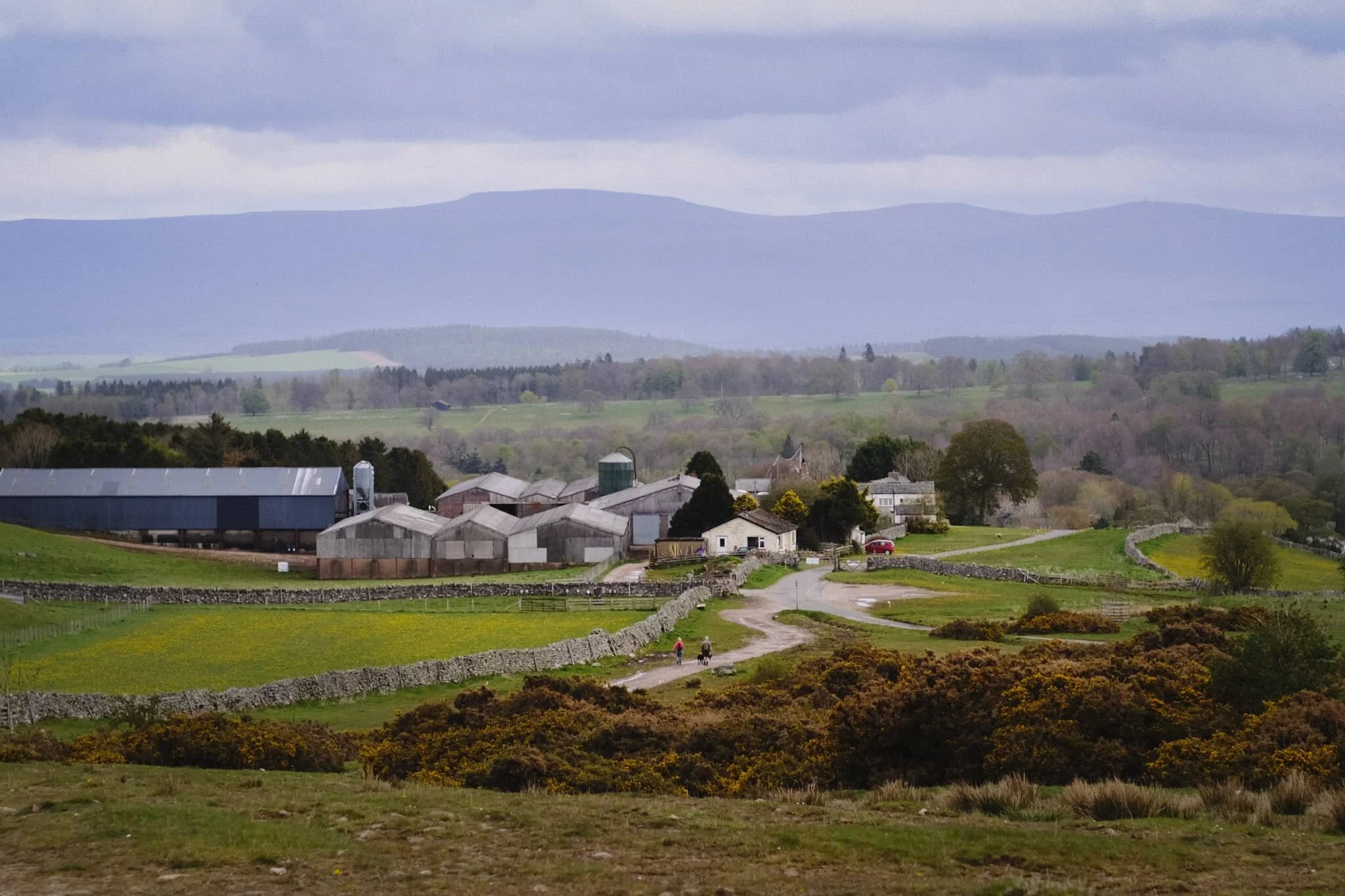 Askham village ahead, with the shadows of Northern Pennines looming above in the distance. The village is rather beautiful, and features a large share of houses and buildings many centuries old.