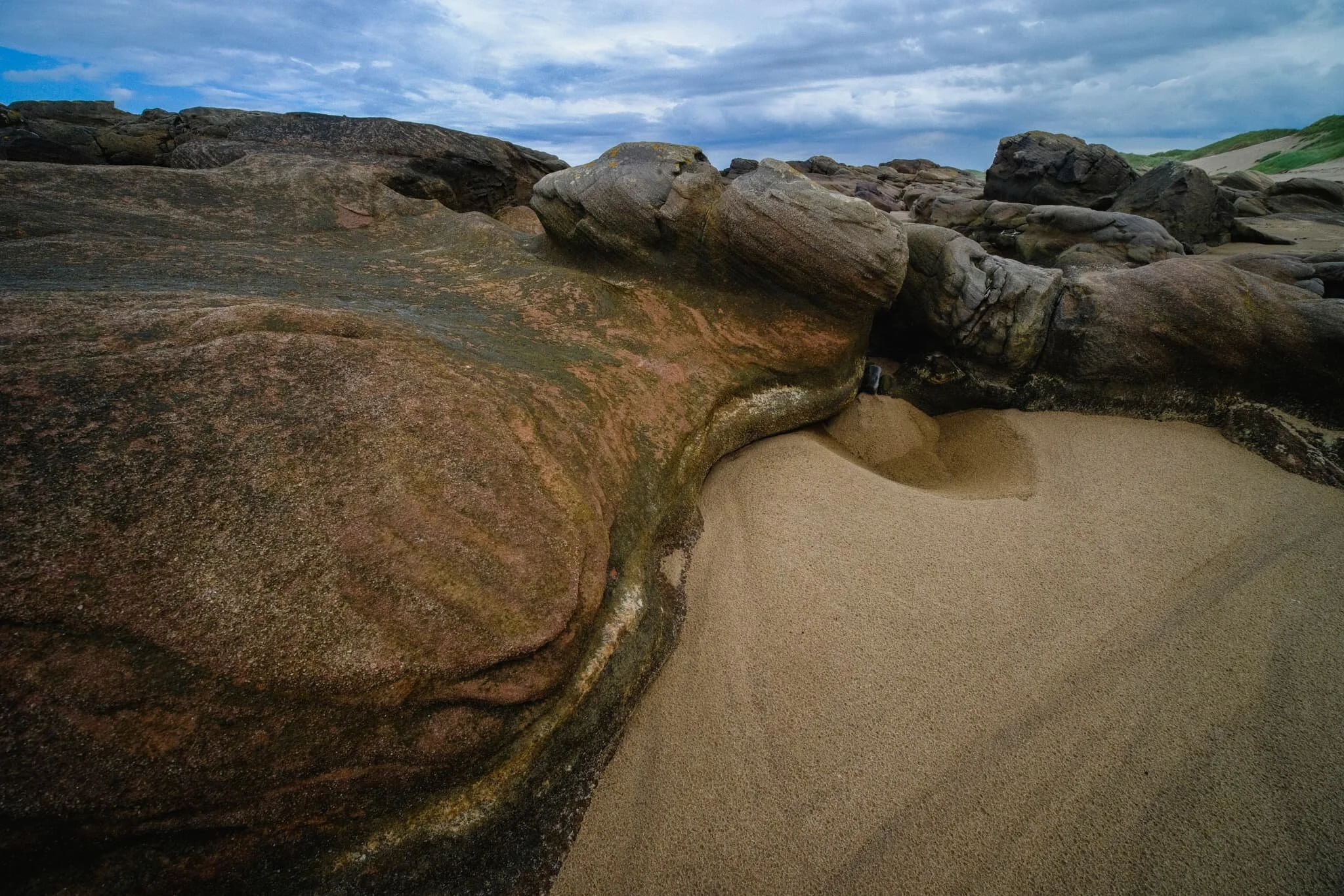 Curving flowing lines and pure untouched sand with a dramatic sky above.