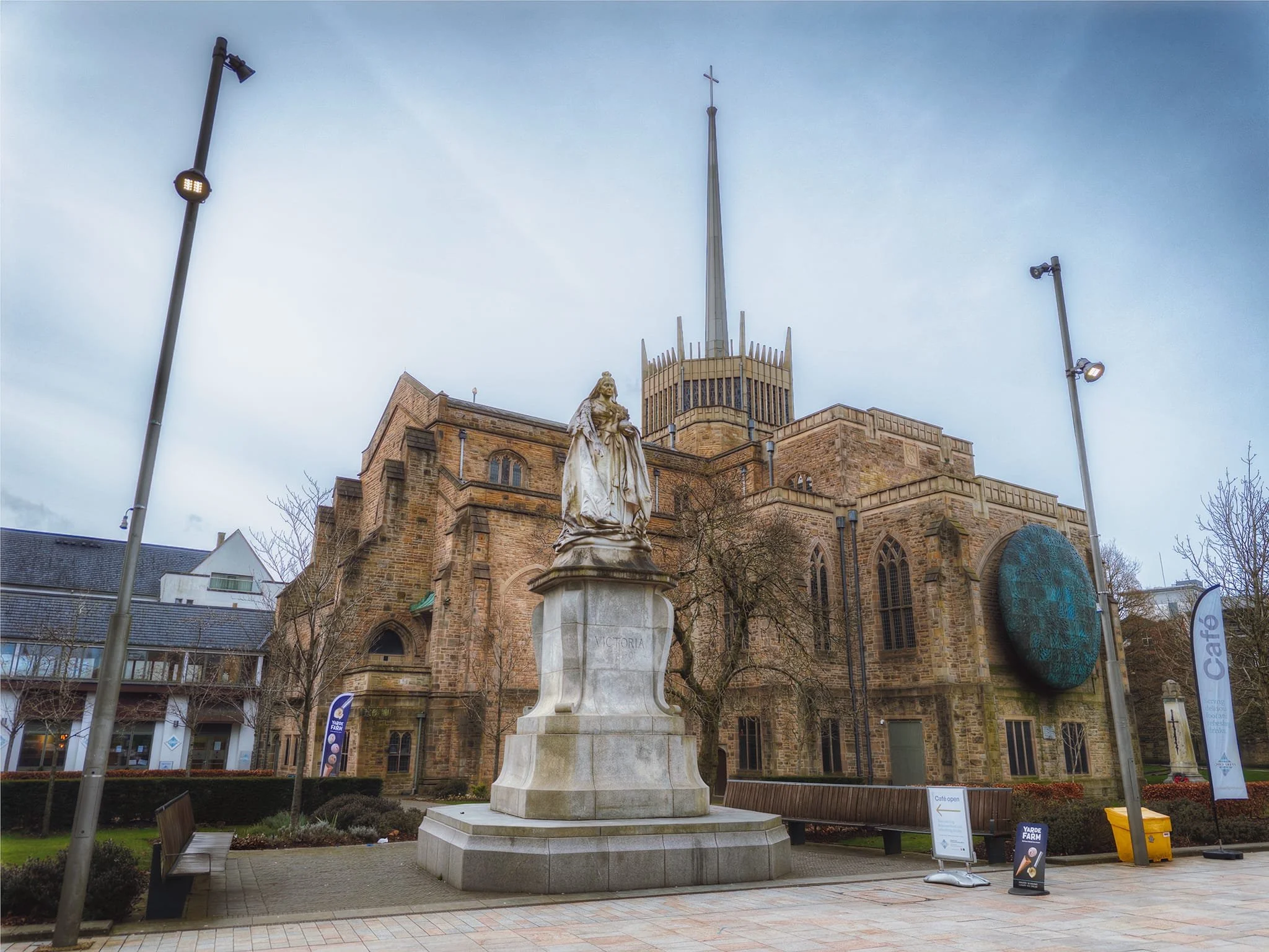 The statue of Queen Victoria, unveiled in 1905, within the grounds of Blackburn Cathedral where its distinctive aluminium 118m tall spire rises high.