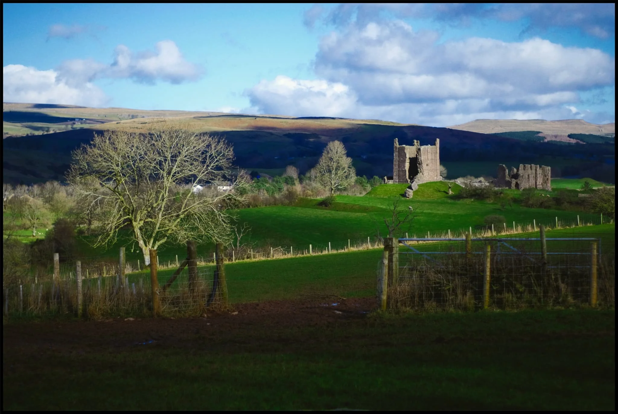  Though the day was sunny and clear, there was a strong and bitingly cold wind. This meant the sun made intermittent appearances, variously scanning across the land in many patterns. Upon spotting this composition, I lined everything up and simply waited for the sun to break free of the clouds again to highlight the castle ruins. 