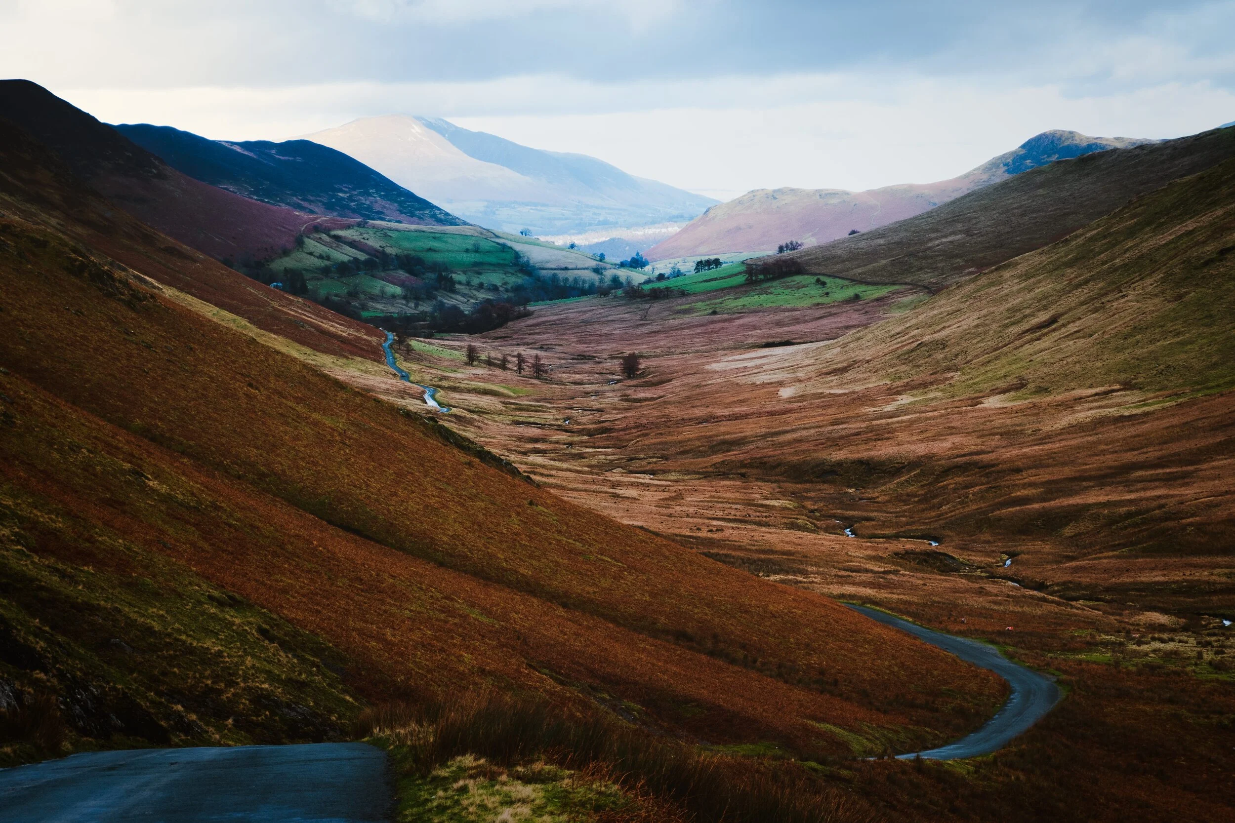 An expansive view of the western section of the Newlands valley, shot from near the summit of the Newlands Pass. In the distance, Blencathra (868 m/2,848 ft) catches some golden light from the setting sun.
