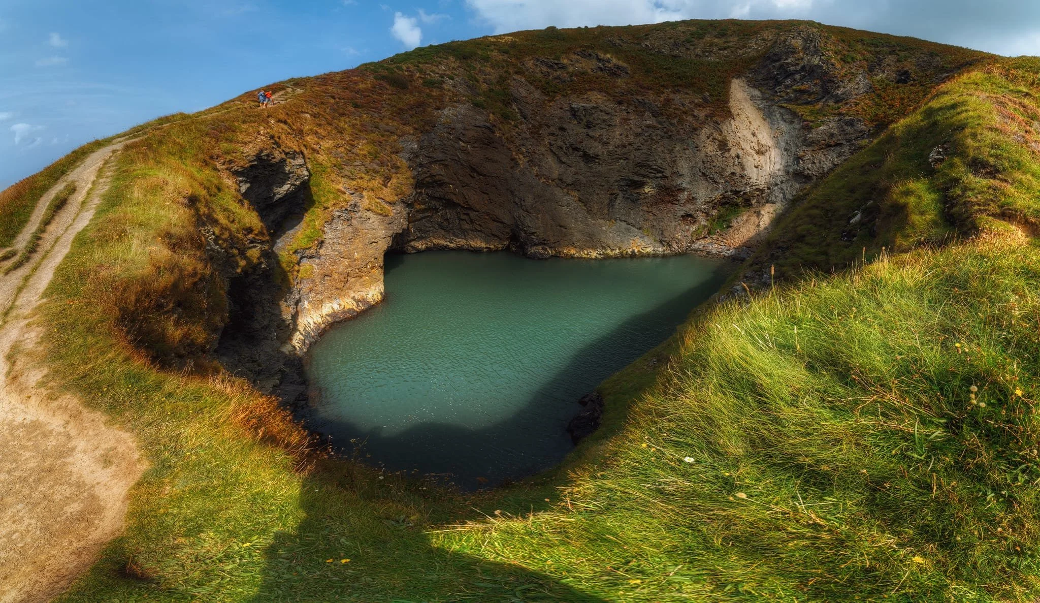  The path steeply descends down to  Pwll y Wrach , the Witches Cauldron. It&rsquo;s a striking geological feature; a collapsed cave, formed where the sea has picked out soft crumbling shales and sandstones along a fault. The crater still connects to the sea and is a popular place for  daring canoeists, which we saw. I attempted to capture the entire expanse of this collapsed cave by shooting five vertical frames at 14mm each, stitching them together into this massive panorama. 