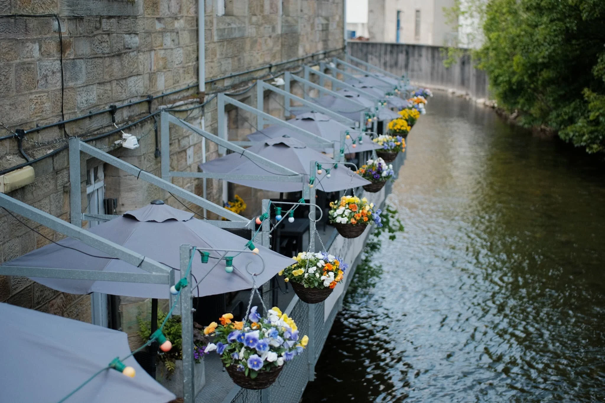 The outdoor seating area of The Honest Lawyer, nicely decorated with hanging flowers alongside the River Cocker.