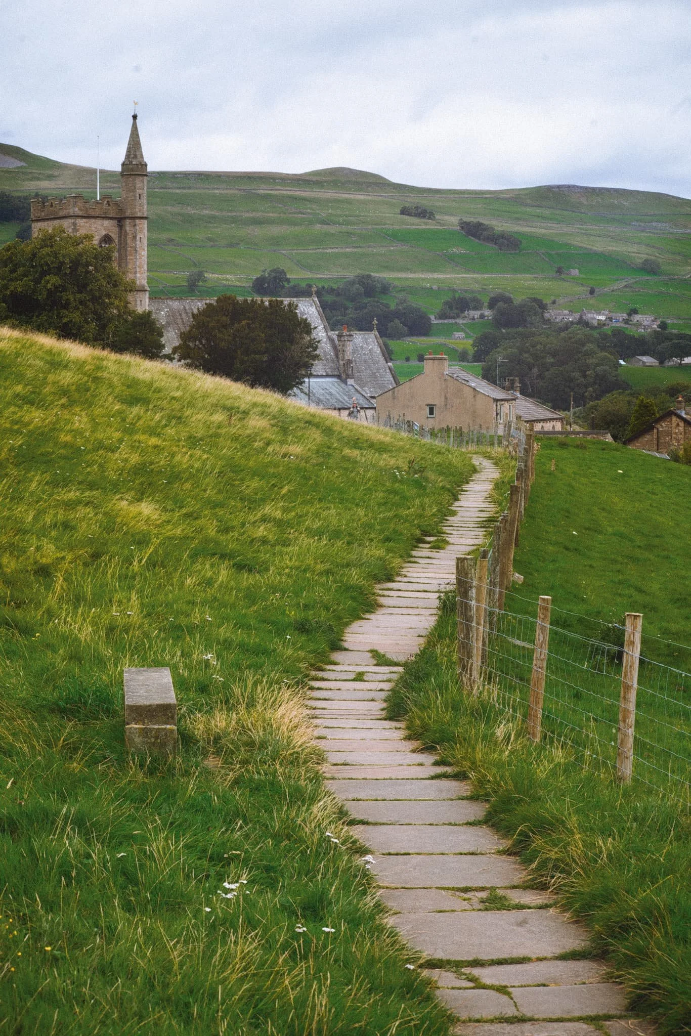 The well-maintained path takes you around the back of Hawes and opens up the views from above it. Here, the path serves as a leading line past St. Margaret’s Church and over the buildings of Hawes, with the nub of Smuker Hill, part of Lovely Seat, visible.