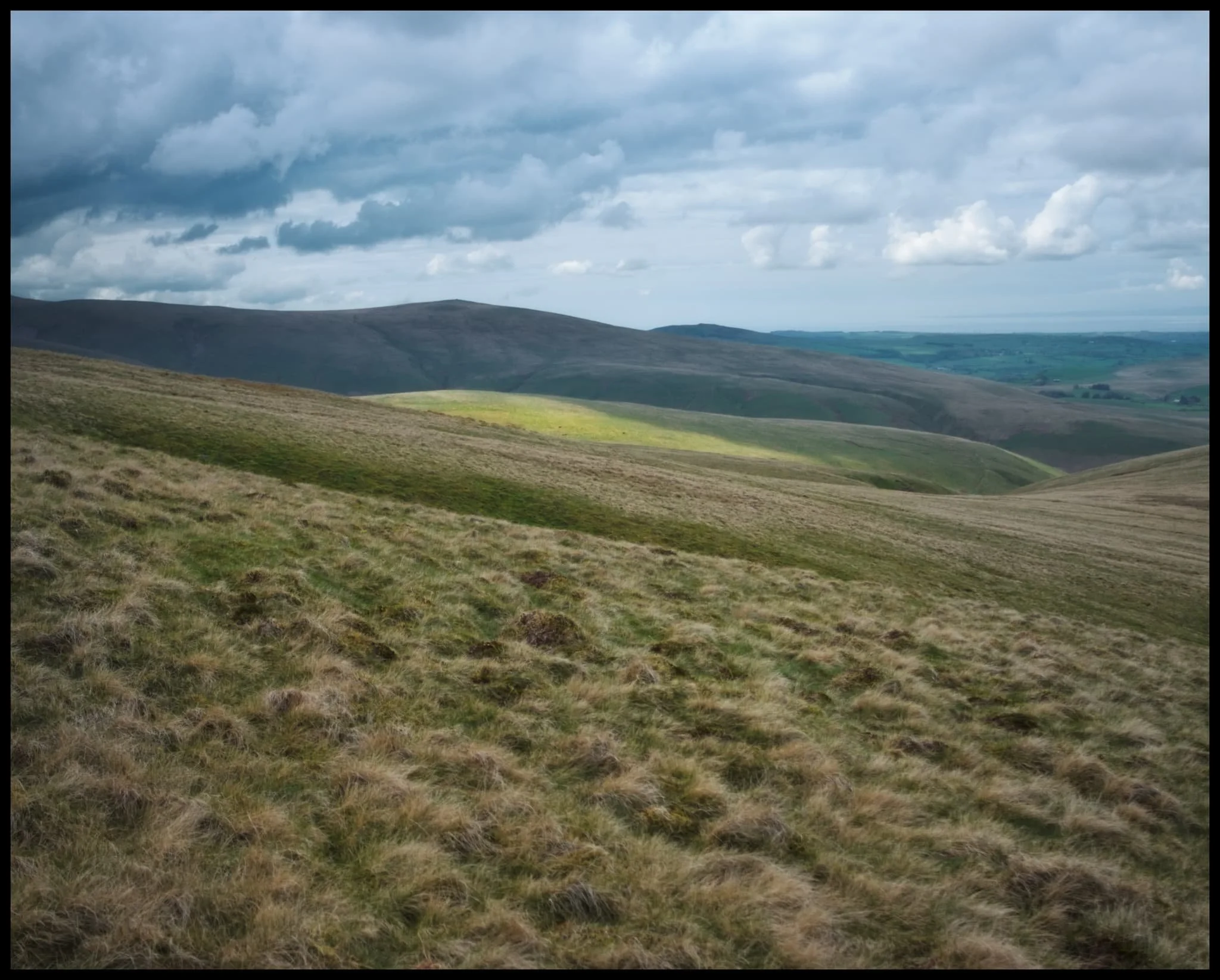  As the continue the climb, slivers of light dance across the fells and sink into the gills. The prominent peak is Brae Fell. 