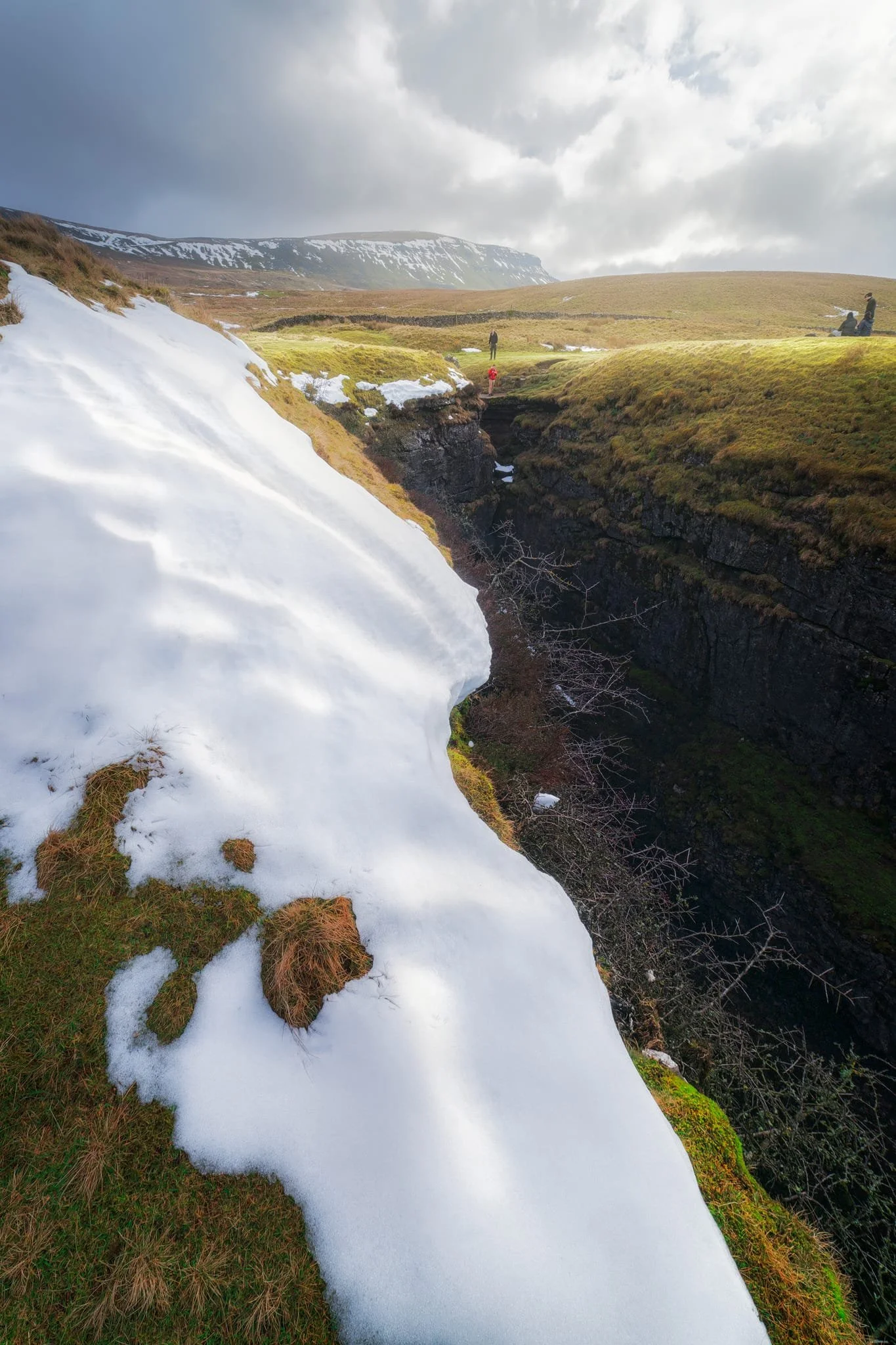  A particularly clean snow patch nearer the falls gives me an idea for a composition involving Pen-y-Ghent in the distance. Fellow hikers milling about the edge of Hull Pot give you a sense of scale of this place.  
