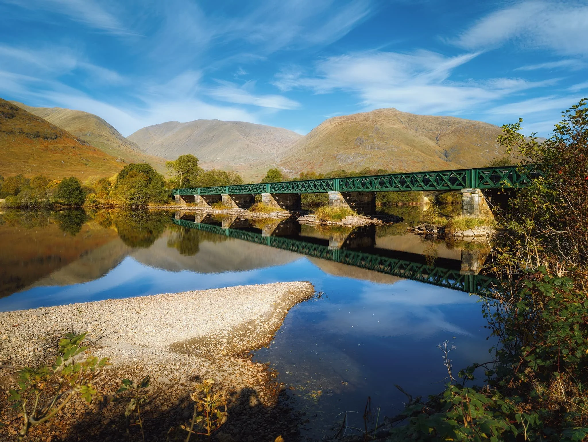  Walking back to the car park, the loch was providing superb reflections that I just had to nail. Here, I utilised the dry shore and the bridge carrying West Highland Railway line as zig-zag leading lines deeper into the composition towards the mountains. 