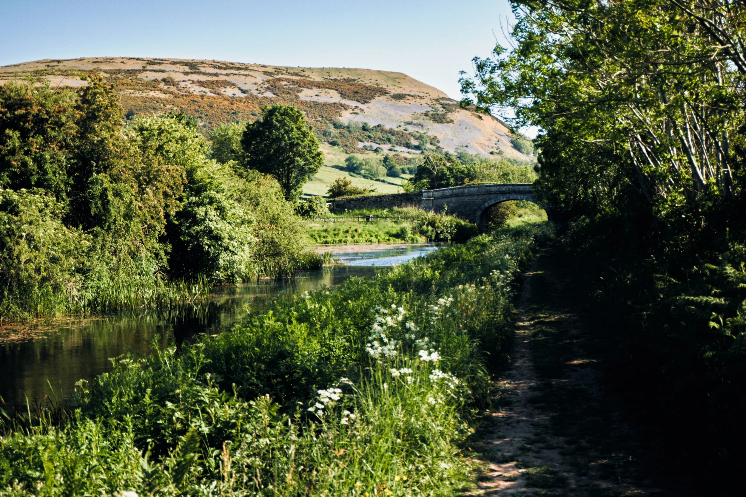After passing Moss Side Culvert (Nº 162), which is where the A65 splits Lancaster Canal, the views start to open up. You can make out Dovehouses Bridge (Nº 161), but more obviously the looming shape of Farleton Fell (265 m/869 ft) comes into view.