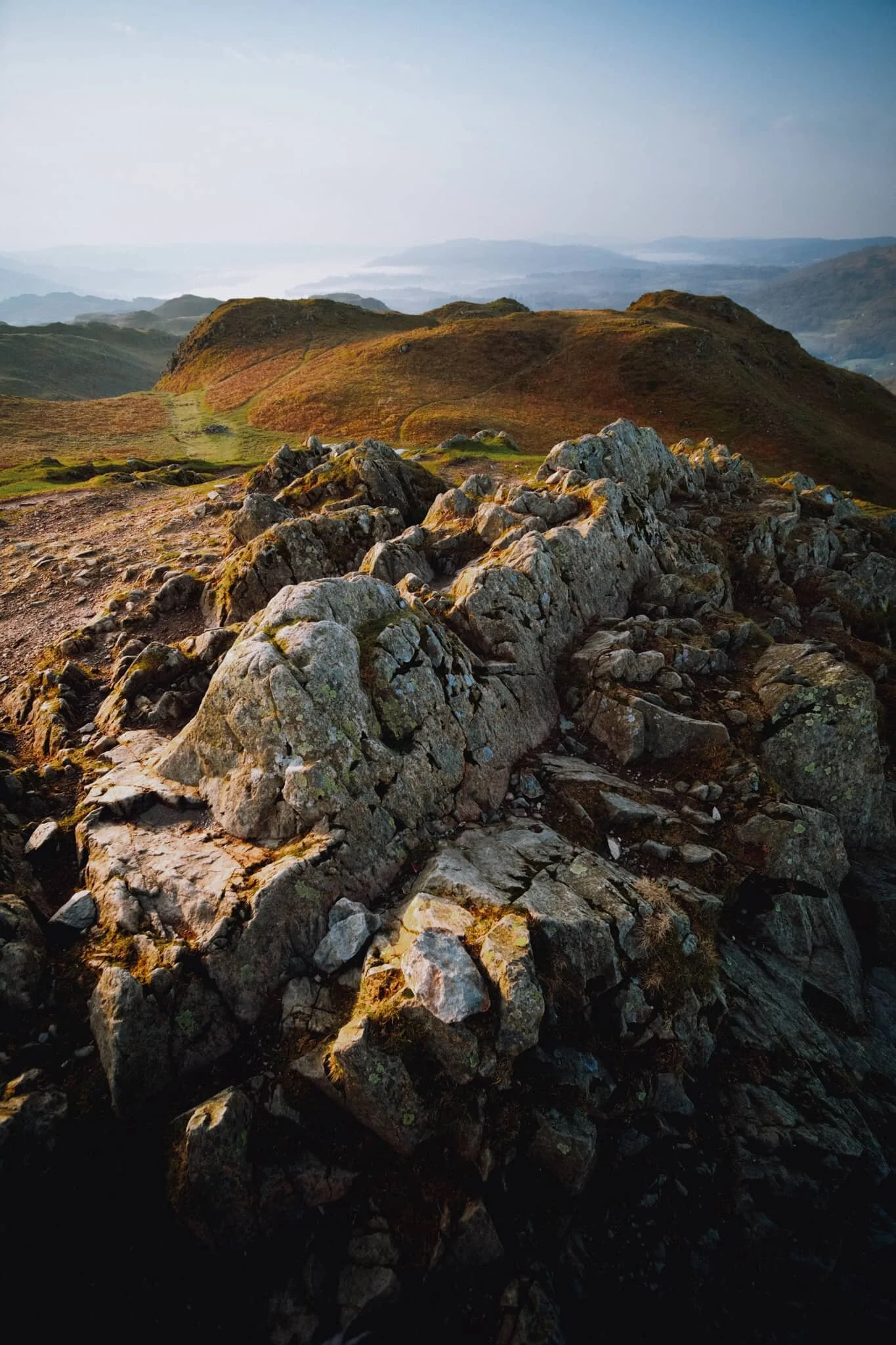  The summit of Loughrigg is wonderfully craggy. My ultra-wide 9mm lens was able to fill the frame with this crag and also take in the extensive view towards Windermere. 