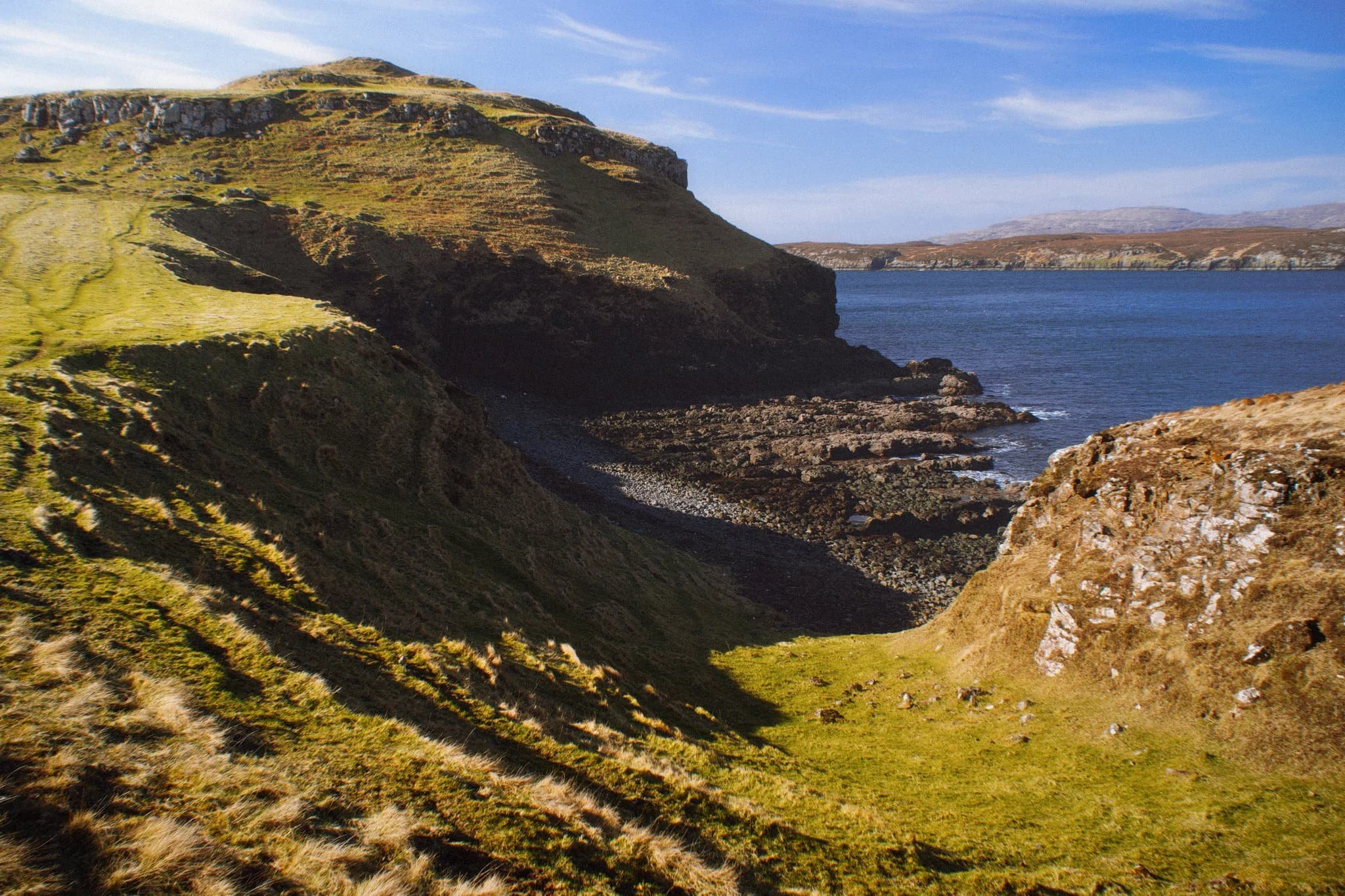  Returning to the lowest part of Oronsay, I venture around its more boggy eastern area for a view back to the craggy cliffs, again using the harsh light and shadow to aid in a leading line composition. 