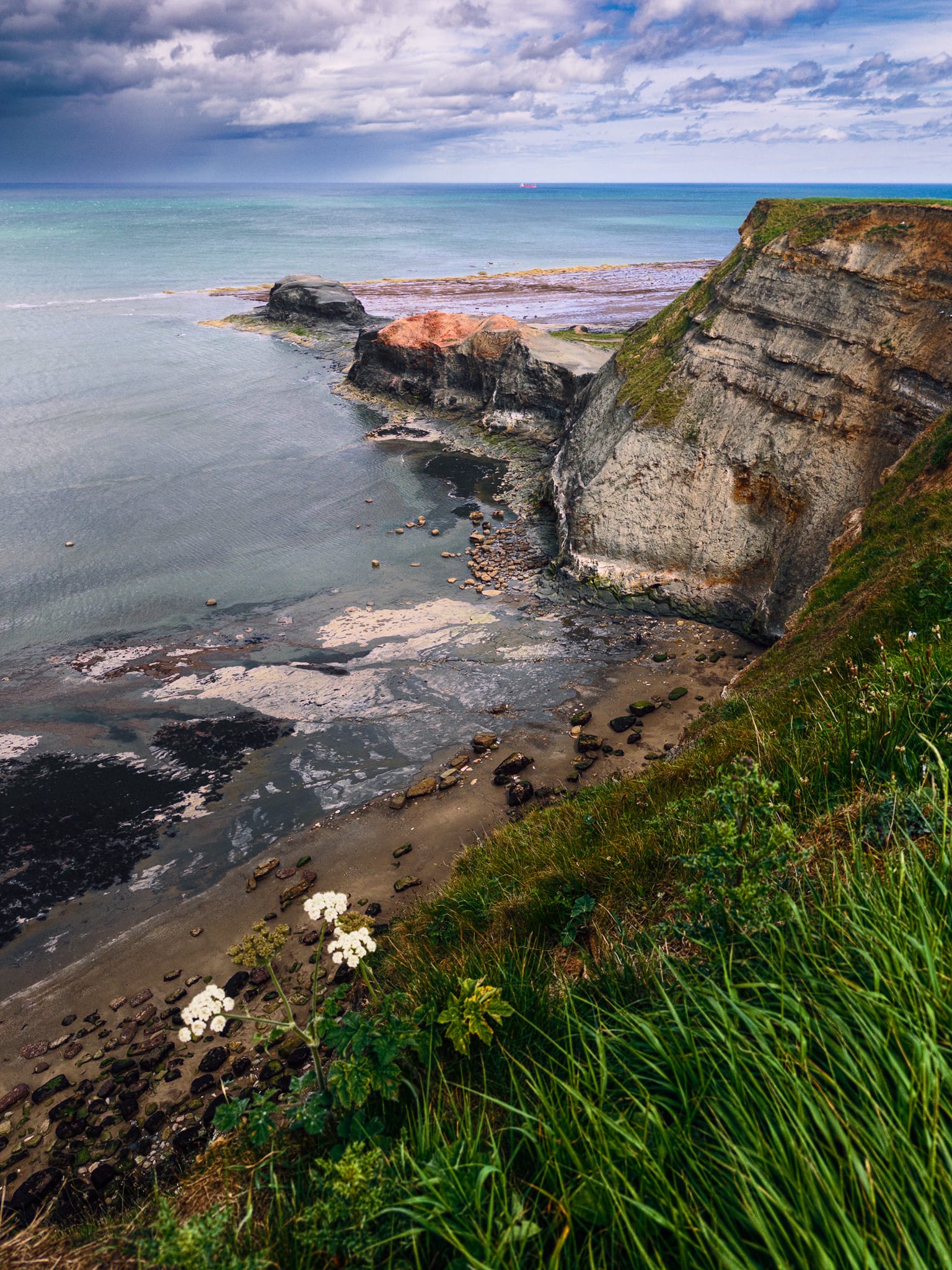 Saltwick Nab as we approached the bay along the cliffs from the west. Evidence of quarring is abundant. Out to the sea a storm dumps water from the clouds. Thankfully, away from land.