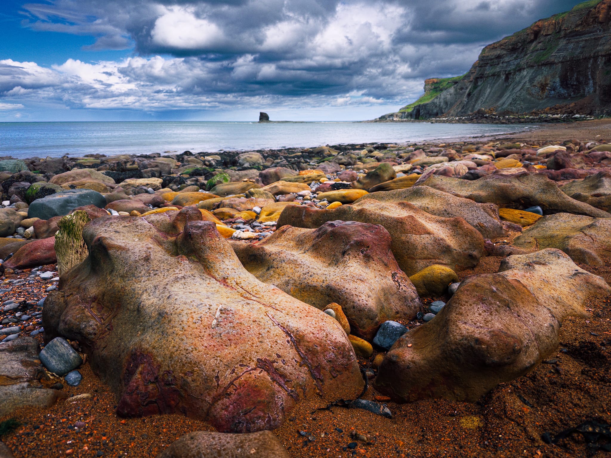 Some more beautifully sculptured boulders. Rounded and smoothed by wave and sand abrasion. The bulbous, hollowed shapes are differential erosion: softer patches wear faster than the iron-cemented parts, leaving that pitted, sculpted texture.
