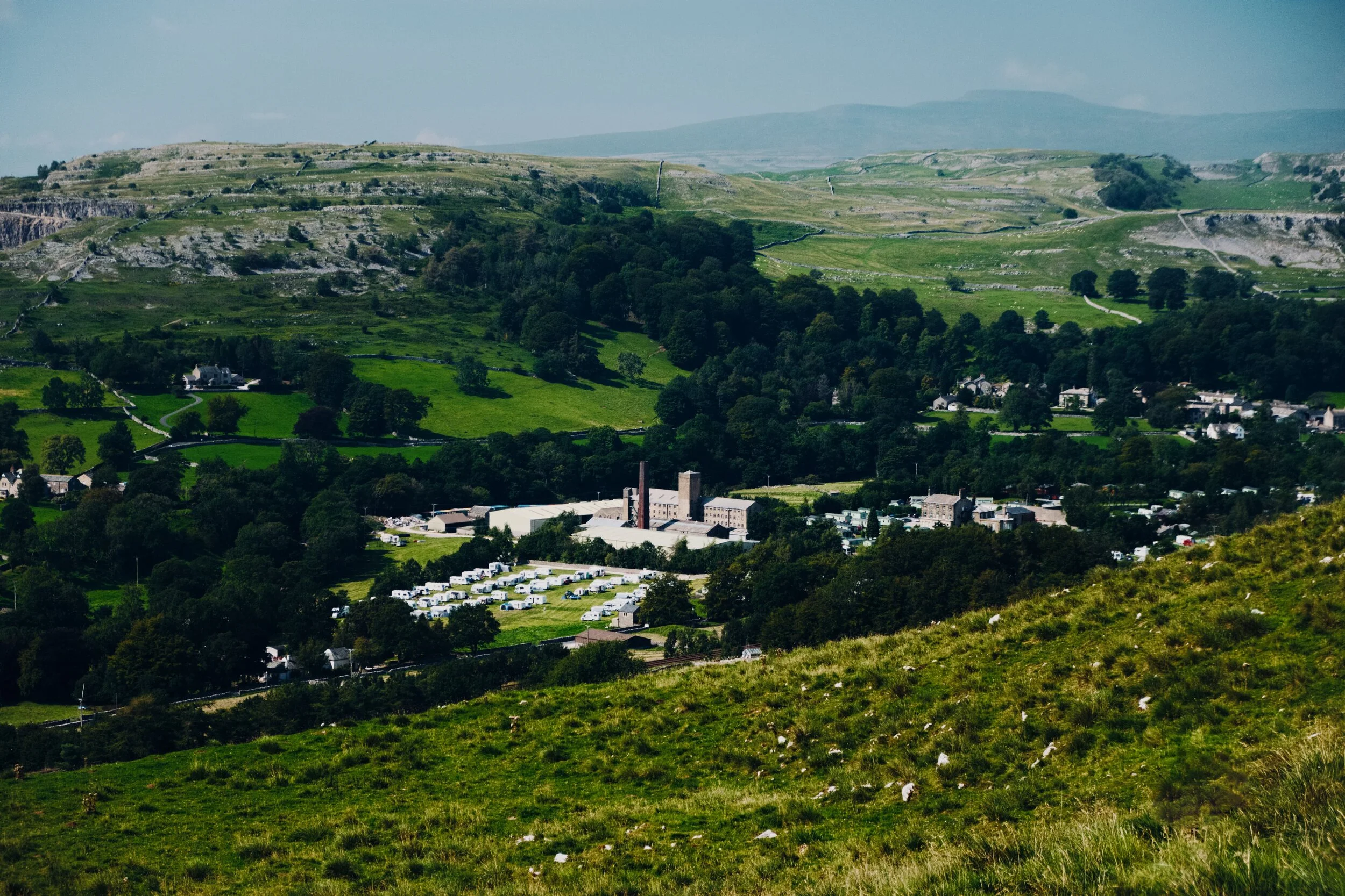 The views back down to Settle and Langcliffe open up. Here you can make out the John Roberts Paper Mill nestled in the valley, a quarry to the left above it, and in the far distance to the right is the unmistakeable shape of Ingleborough (723 m or 2,372 ft).
