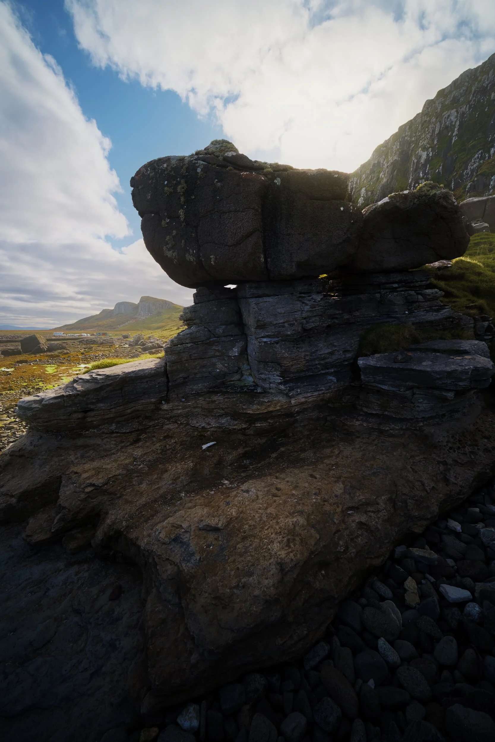 More glacial erratics perched on sculpted formations. In the distance, to the left, are the two cliff faces of Sgeir Bhàn .