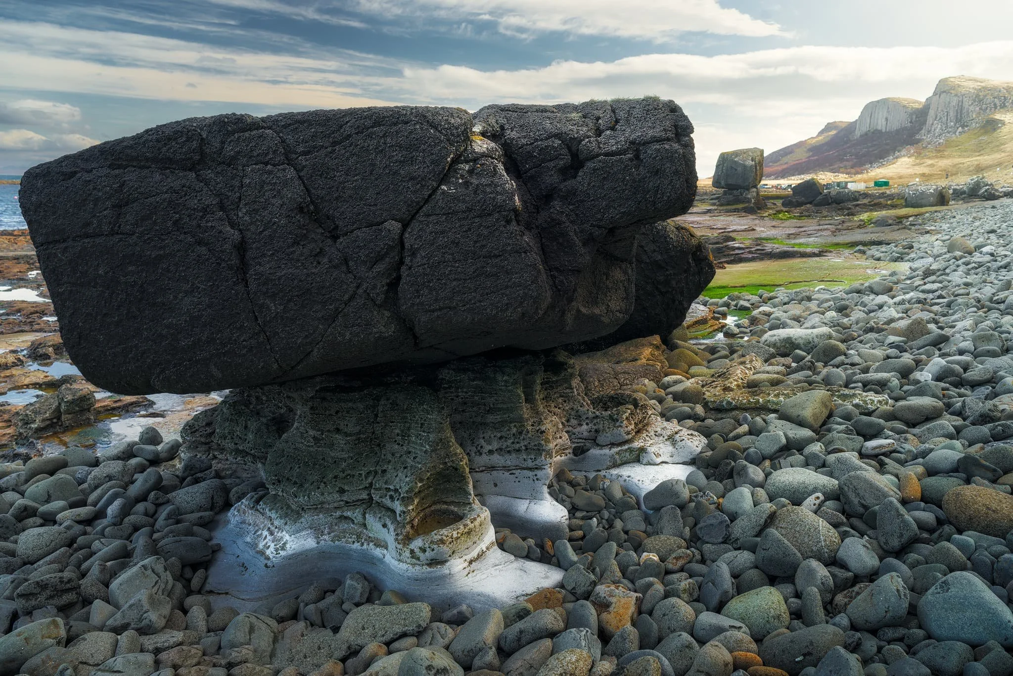  This particular boulder I find amazing. No human intervention whatsoever. A chunk of rock broke off the nearby cliffs, rolled down onto the coastline. Over the course of aeons, water and wind washed and carved the surrounding rock, leaving this boulder sitting on its protected pedestal. 