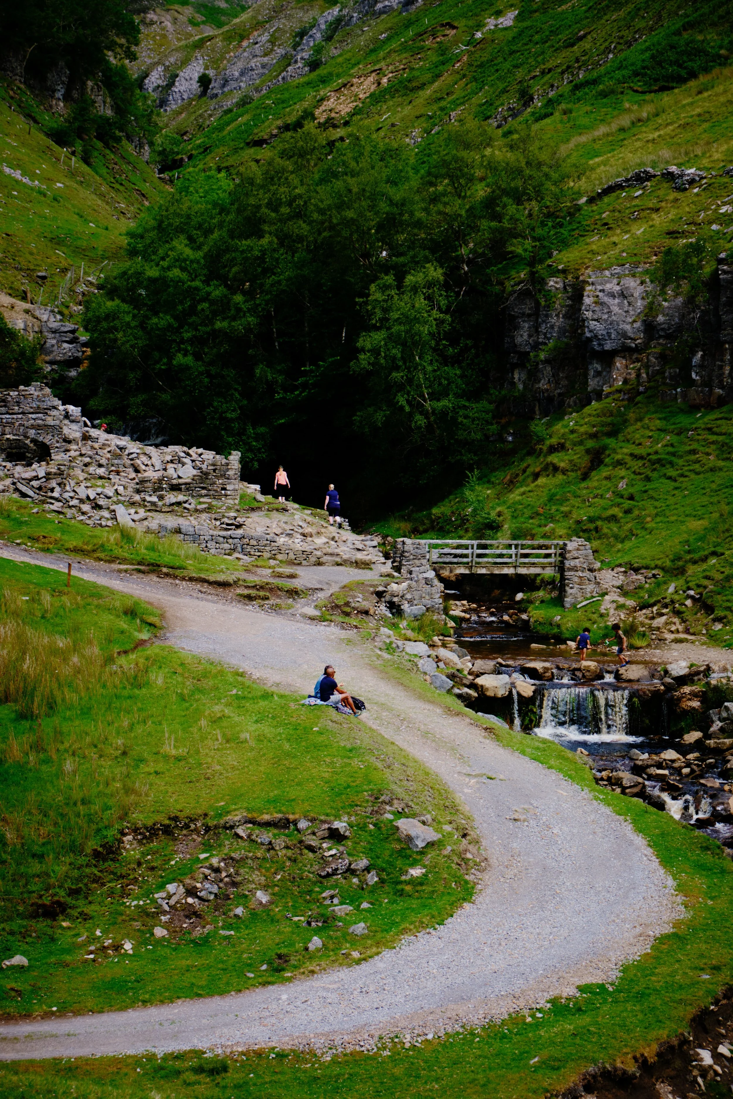 Families and hikers take a rest beside the mouth of Swinner Gill