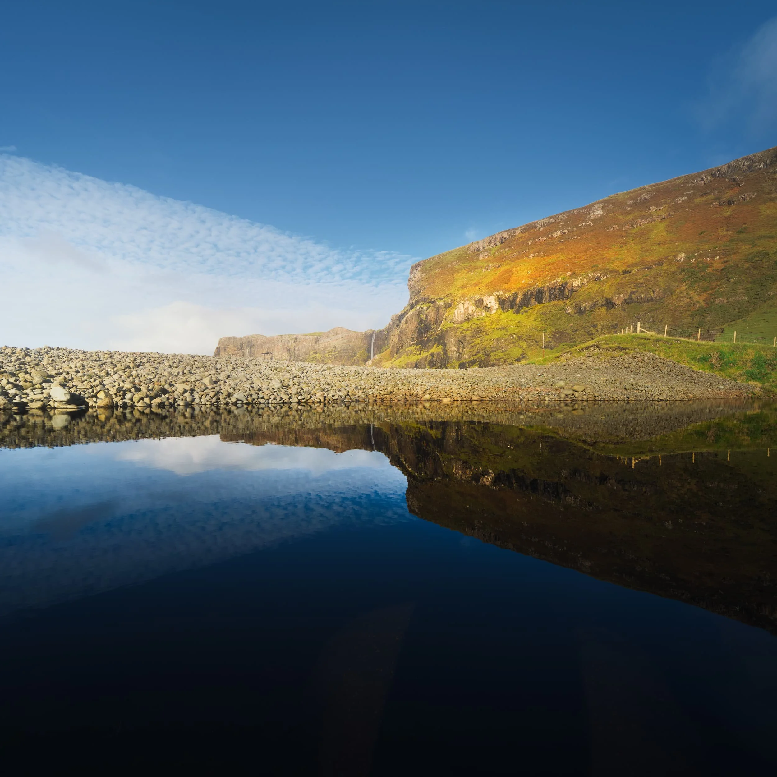  The northern side of Talisker Bay features sheer cliffs and a delightful waterfall dropping right into the sea. The waterfall is the outflow from a small loch just above the cliffs,  Loch an Sgùirr Mhòir . 