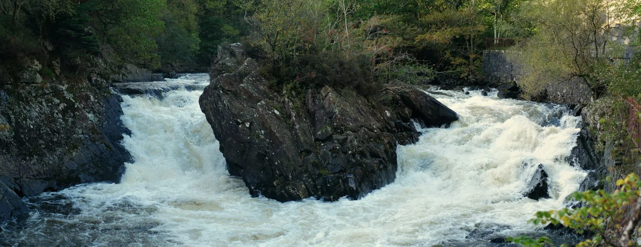  On our way to Balquhidder, we stopped off for a small diversion just south of Loch Lubnaig. There, one can take the barely noticeable trail that follows the main road until the roaring sound of water guides you to this incredible scene. These are the Falls of Leny. This is large panorama shot with my 55mm lens and stitched together to get this incredibly detailed and wide view of the falls. 