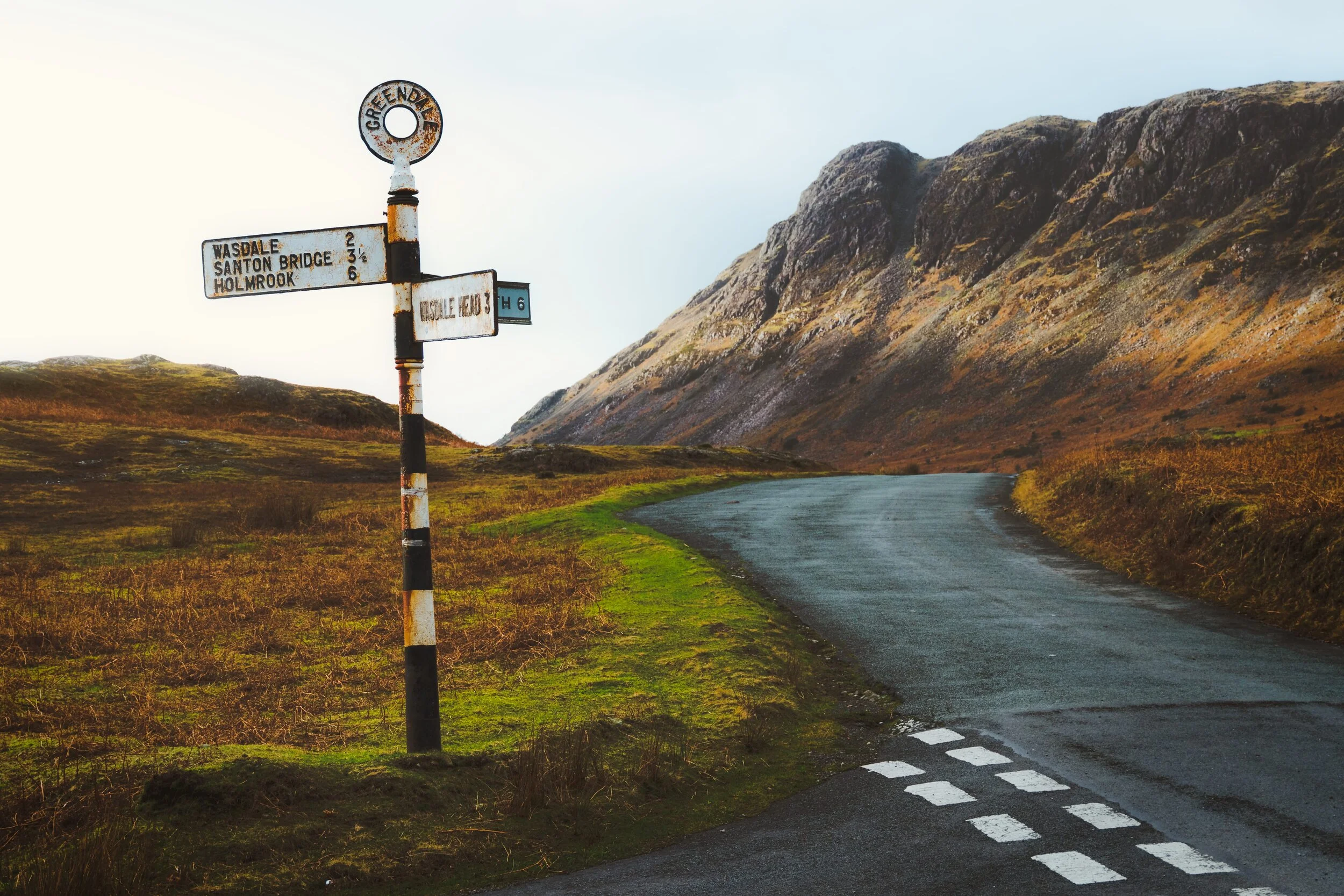 As the sun started to set, more light escaped from underneath the cloud shelf and a beam scraped along the face of Buckbarrow (423 m/1,388 ft) as we neared our car. Wasdale still hosts these Victorian-era sign posts that I find so endearing.