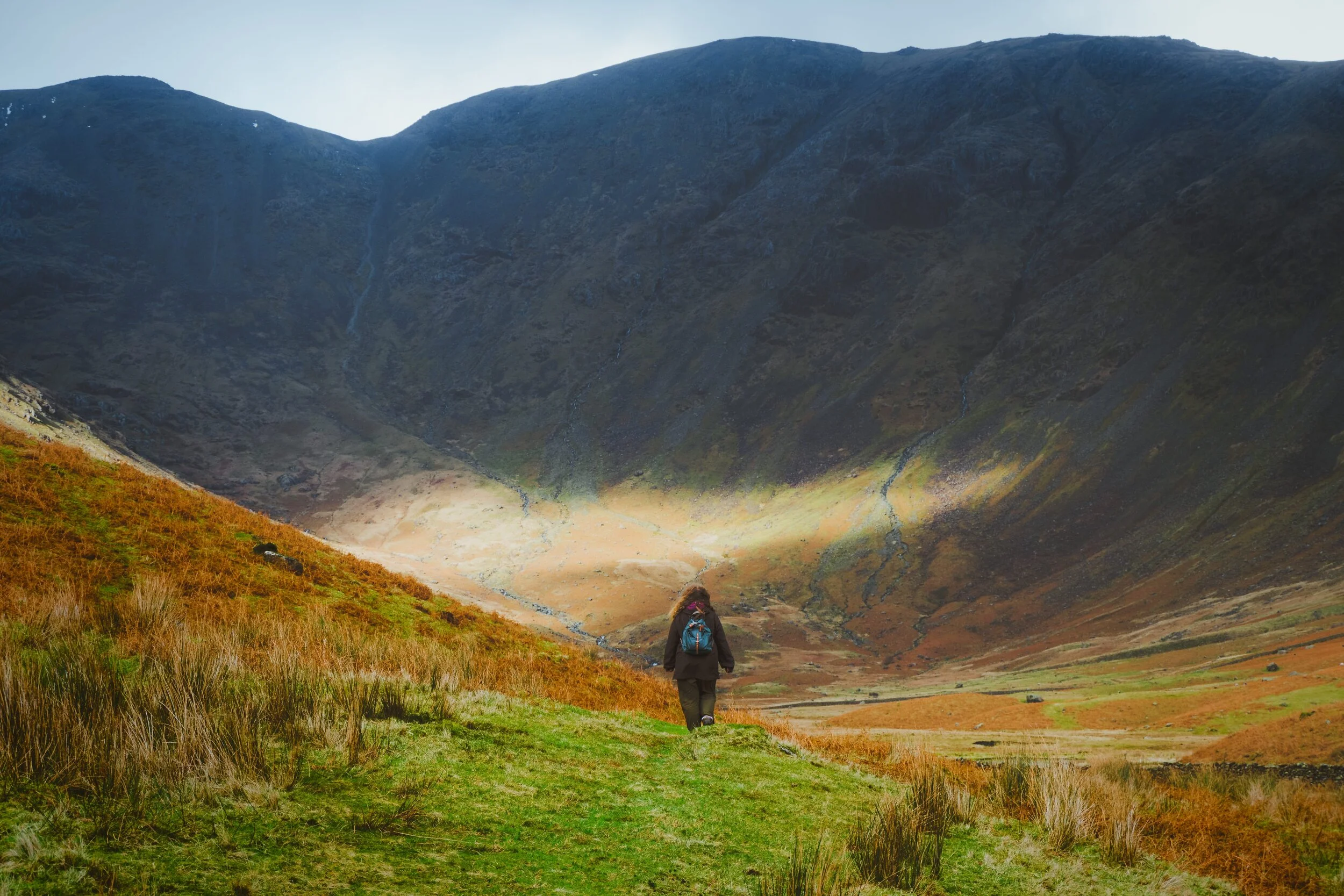 My wonderful Lisabet, looking tiny in the face of Pillar’s (892 m/2,927 ft) sheer southern wall. A small band of light escaped from the clouds behind us to hit the wall.