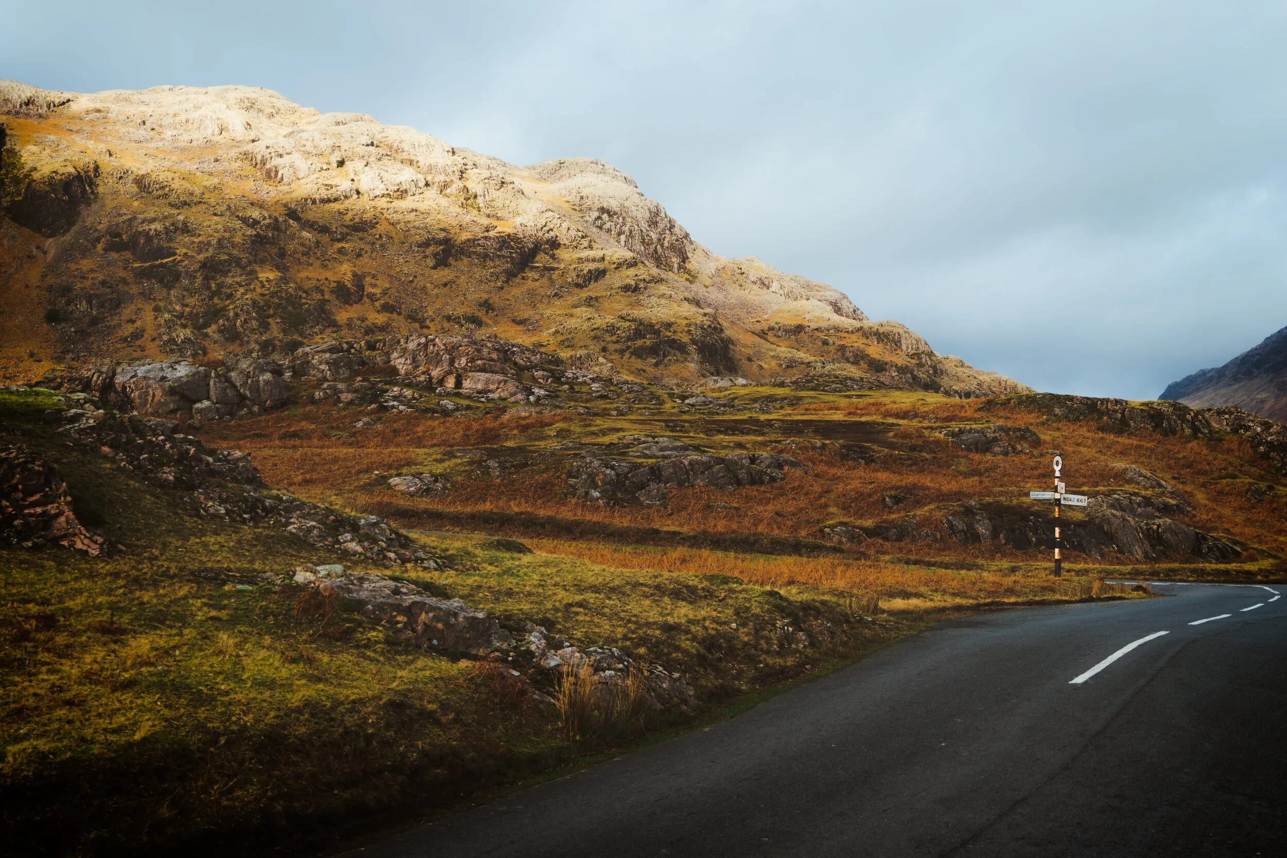 Looking back at the old sign post as another beam of light hits one of the many crags that surround Wastwater.