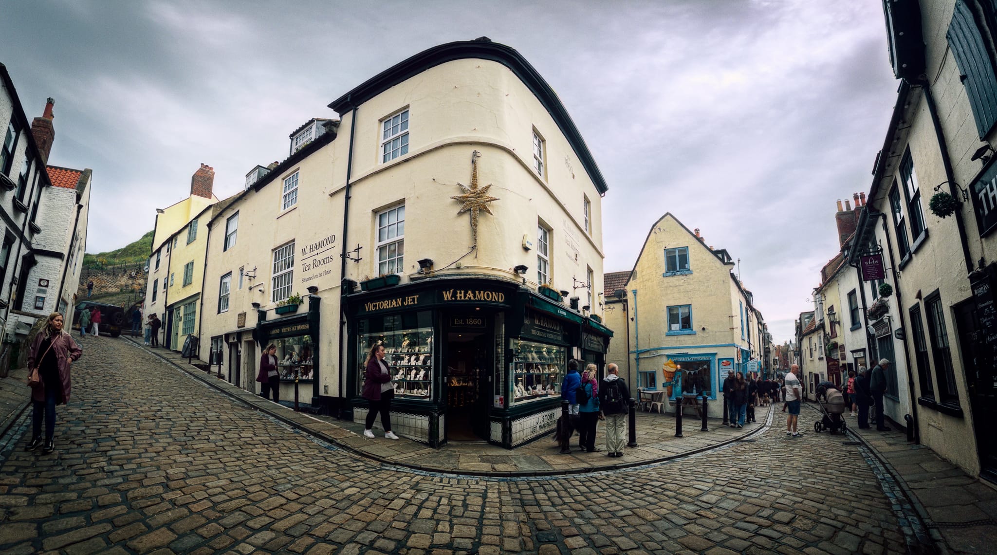 The iconic storefront of W Hamond - The Original Whitby Jet Shop, captured within a panorama. Established by James Storr in 1860, W Hamond is the town&rsquo;s oldest surviving manufacturer and retailer of genuine Whitby Jet jewelry. Operated continuously from this exact same street corner for over 165 years. Crikey.